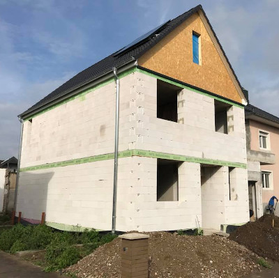 Ein Einfamilienhaus im Bau mit weißen Betonblöcken und einem Dach im Aufbau.